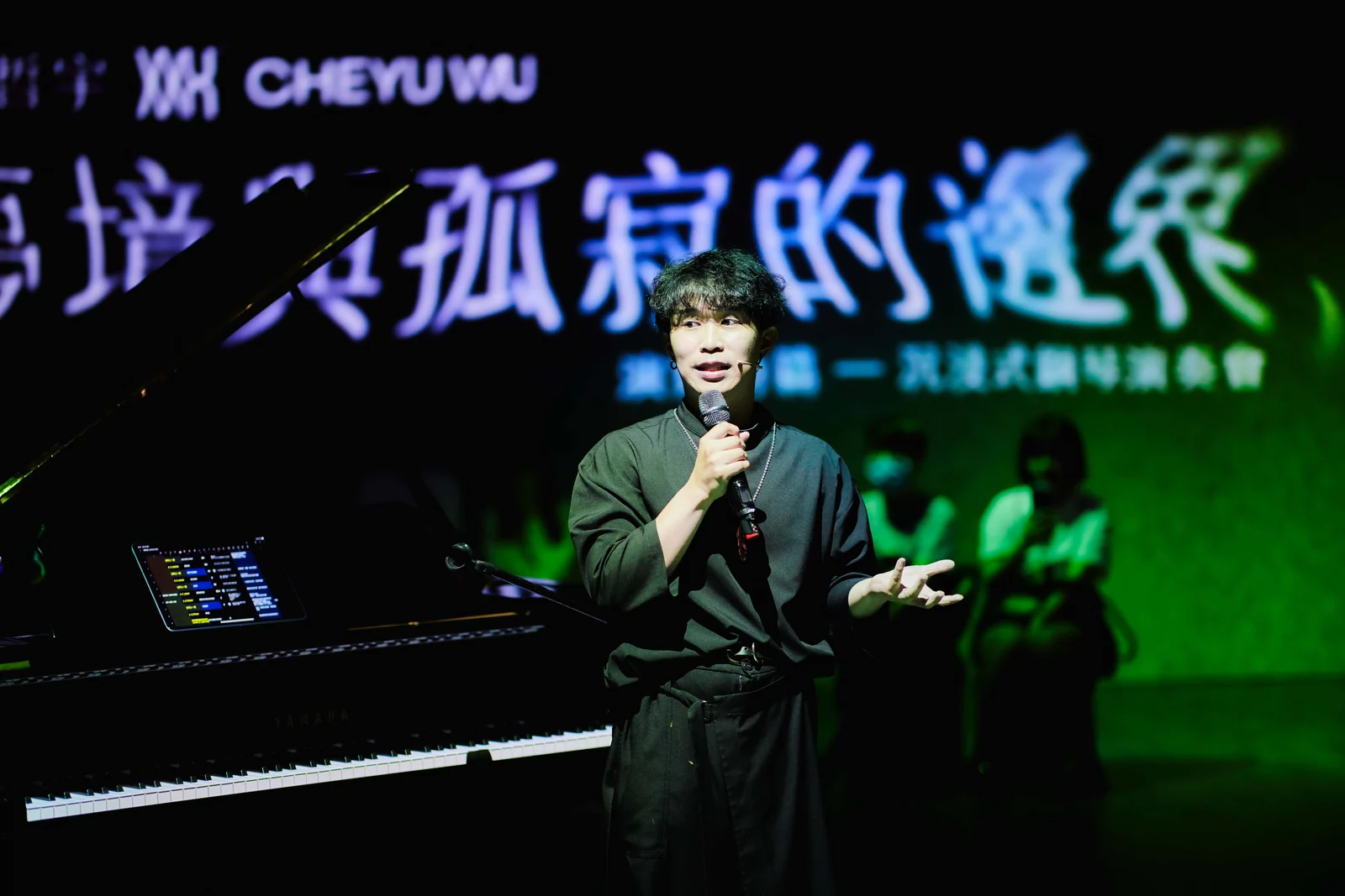他拿起麥克風，身後是演出的標題