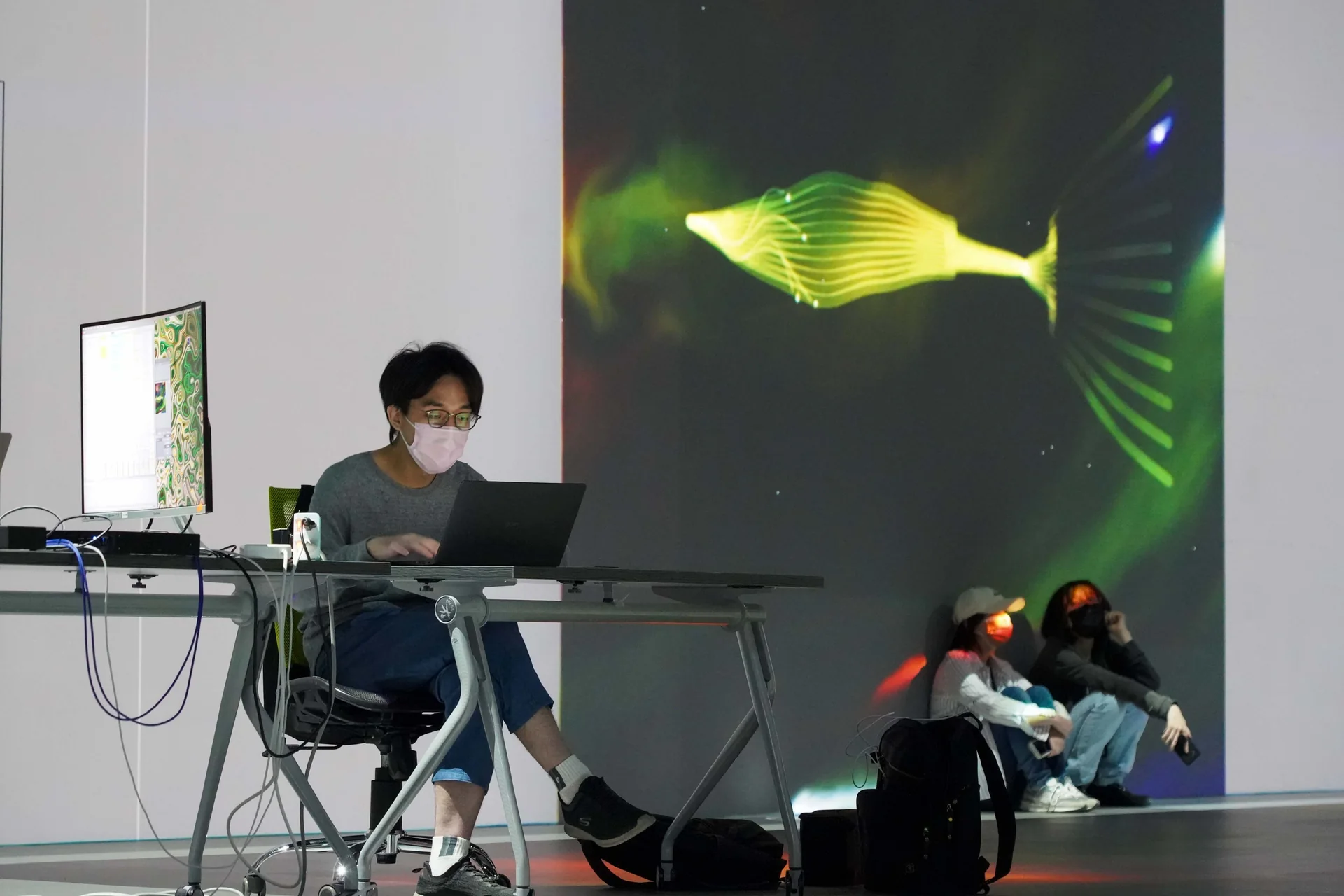藝術家在筆電前演出，牆上是一隻靈魂魚