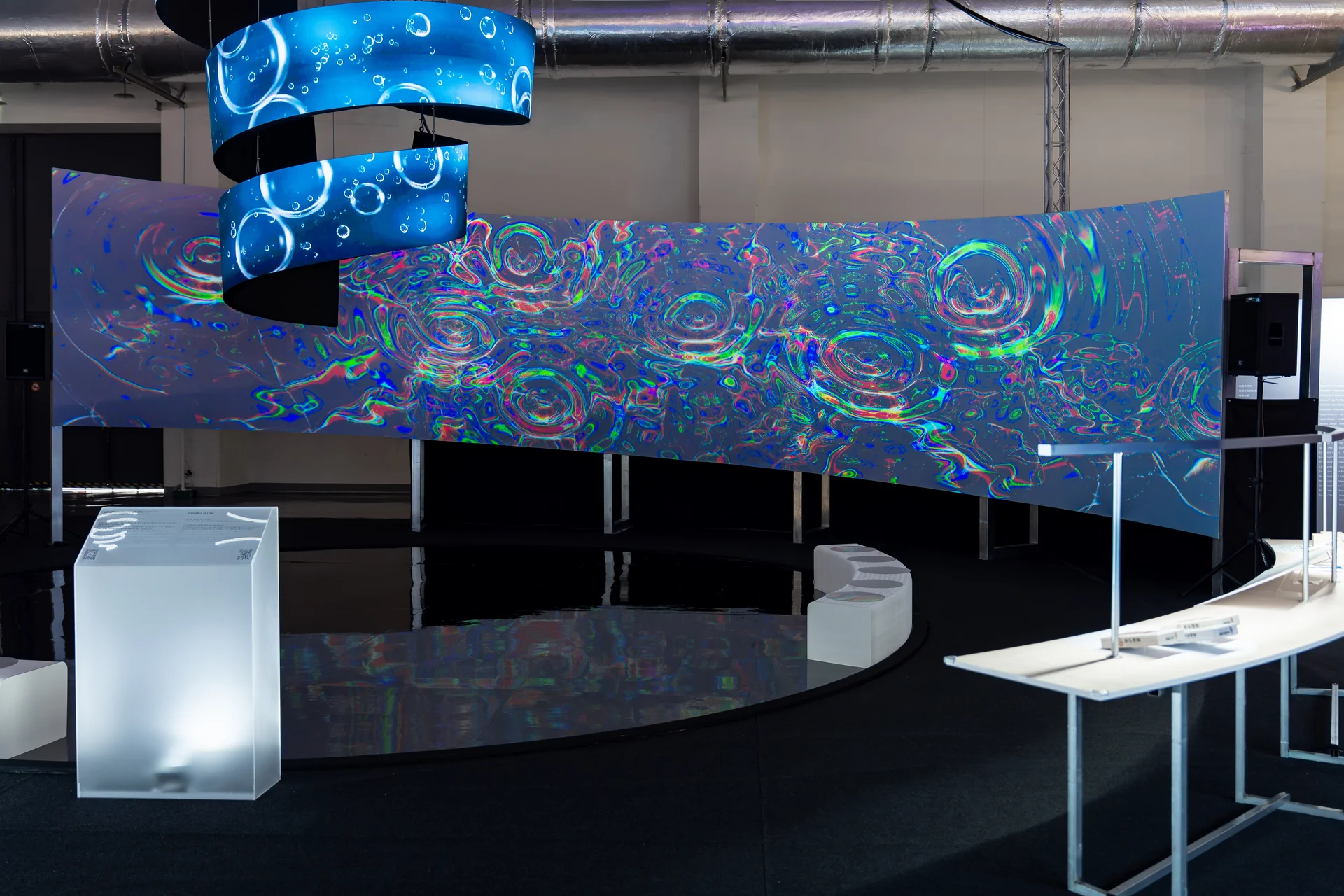 Cymatics of Life on site: The whole wall, colour from dispersed light floating on the ripples