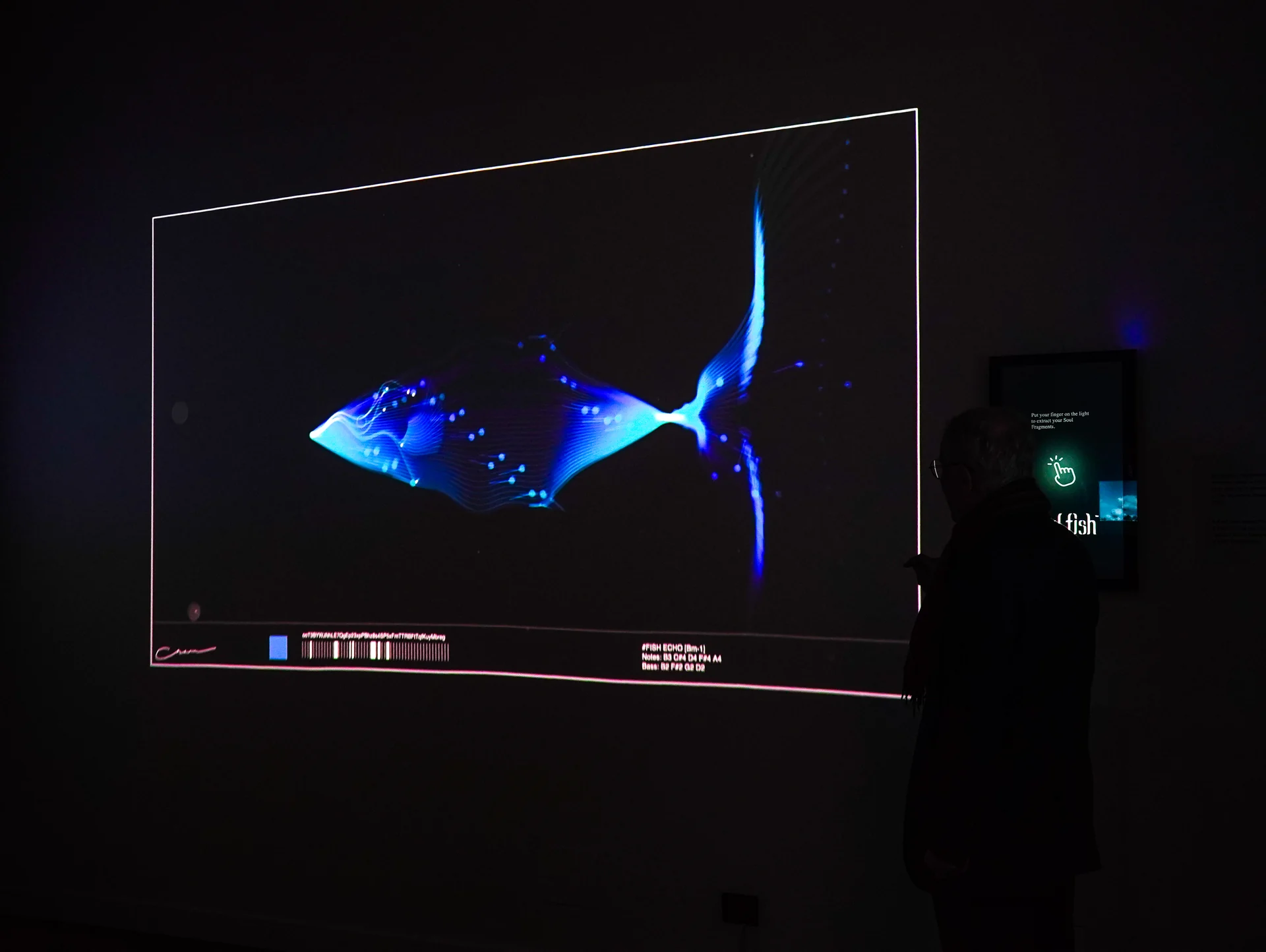 Soul Fish on site: Venice, 2024: a visitor at the touchscreen, a blue fish on the wall