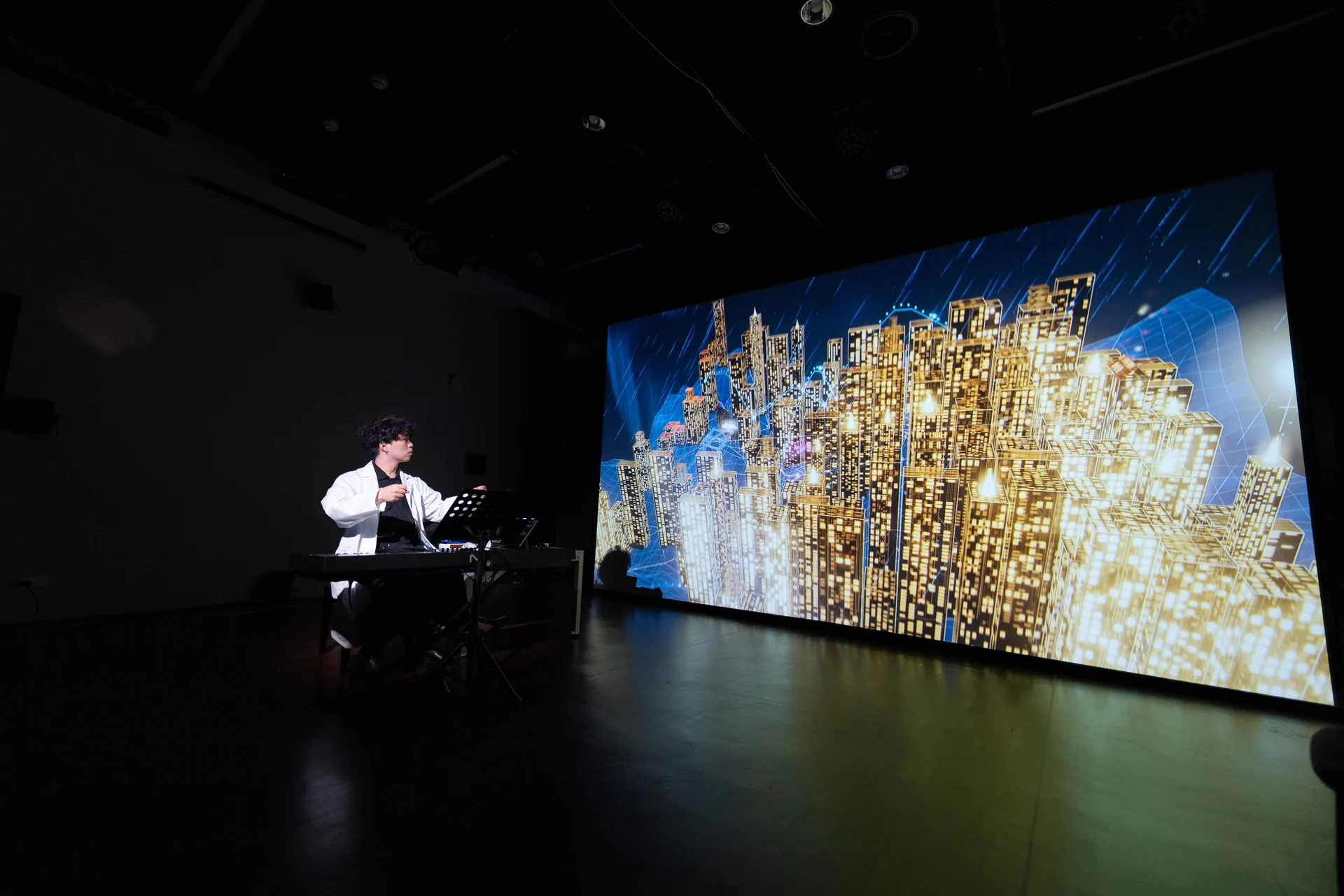 The Last Input rehearsal: a golden city across the whole wall, the performer in a white coat at the piano