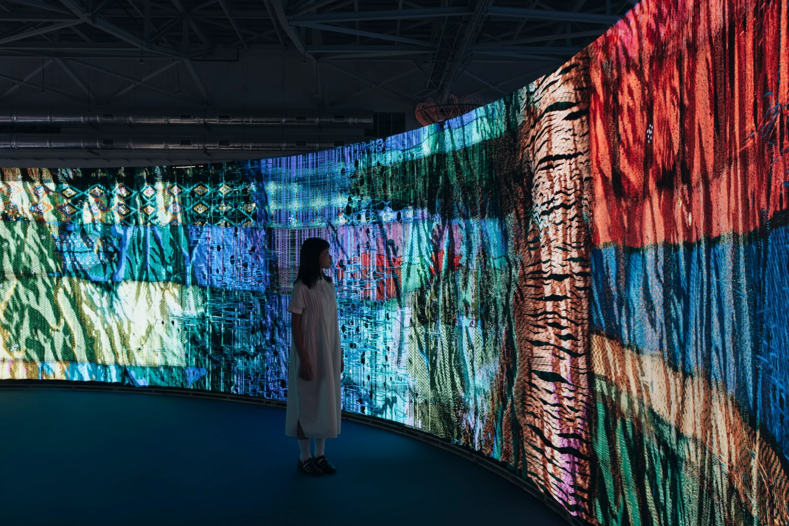 Woven Land, Woven River in the pavilion: A figure in white before the cloth as it turns the corner